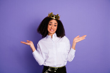 Young woman wearing a crown while gesturing puzzled expression against vibrant purple background
