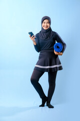 A woman in a black skirt and black pants is holding a blue yoga mat