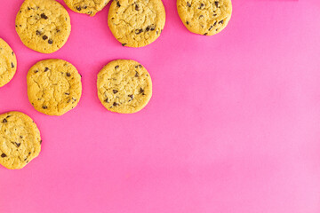 A row of chocolate chip cookies on a pink background
