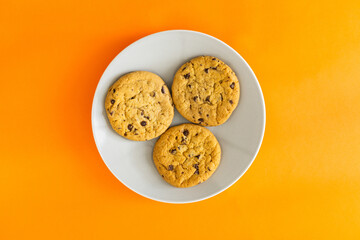 Three chocolate chip cookies on a white plate