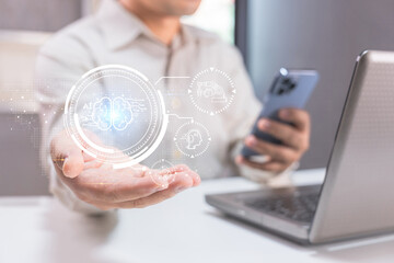 A person holds a smartphone near a laptop, interacting with a digital AI hologram, symbolizing advanced technology and artificial intelligence.