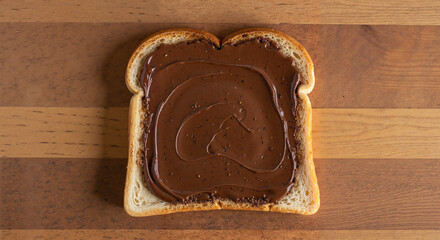 Sliced bread topped with chocolate spread on wooden table