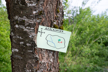 Geocaching, outdoor recreational activity, navigation to hide and seek containter, geocache location in forest, treasure hunting game, note on tree trunk