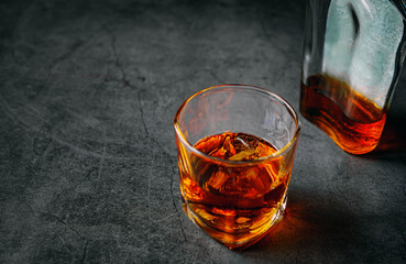 Strong alcohol drink and whiskey bottle Whisky in glass with ice, Whisky, bourbon or cognac. Hard strong alcoholic drink