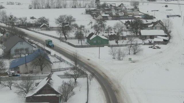 Aerial Drone Shot of Old Truck Driving Through Snowy Rural Landscape