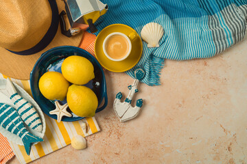 Mediterranean summer vacation concept with straw hat, lemons and coffee cup on striped towel background. Top view, flat lay