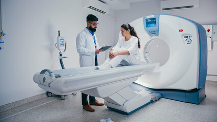 Engaged woman observing X-ray together with her doctor while listening. Male doctor in glasses...