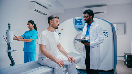 Male patient explaining symptoms while African American doctor holding tablet listening...