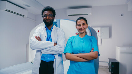 Smiling doctor standing confidently with arms crossed beside cheerful female nurse in uniform. Both...