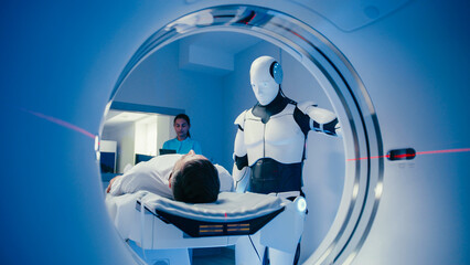 Humanoid robot standing beside MRI tunnel while observing Caucasian man lying still on examination...