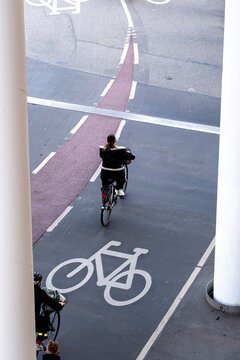 Cyclists using a bike lane marked with white bicycle symbols in Copenhagen illustrating the integration of cycling and city traffic