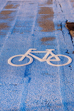 Bicycle lane sign painted on asphalt in Copenhagen showing a white bicycle symbol on a blue path for cyclists in urban traffic design