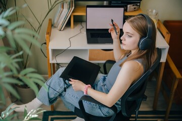 Young graphic designer working from home using graphics tablet and laptop