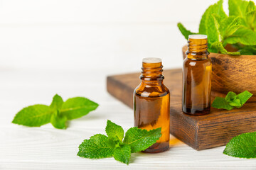 Essential oil mint on a wooden background. Peppermint essential oil with fresh mint leaves. A bottle of aromatherapy oil. Mint extract. The concept of natural cosmetics, spa care. copy space
