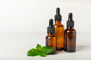 Essential oil mint on a wooden background. Peppermint essential oil with fresh mint leaves. A bottle of aromatherapy oil. Mint extract. The concept of natural cosmetics, spa care. copy space