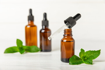 Essential oil mint on a wooden background. Peppermint essential oil with fresh mint leaves. A bottle of aromatherapy oil. Mint extract. The concept of natural cosmetics, spa care. copy space