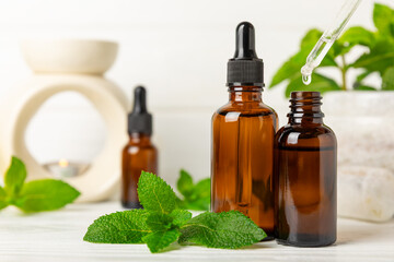 Essential oil mint on a wooden background. Peppermint essential oil with fresh mint leaves. A bottle of aromatherapy oil. Mint extract. The concept of natural cosmetics, spa care. copy space