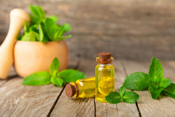 Essential oil mint on a wooden background. Peppermint essential oil with fresh mint leaves. A bottle of aromatherapy oil. Mint extract. The concept of natural cosmetics, spa care. copy space