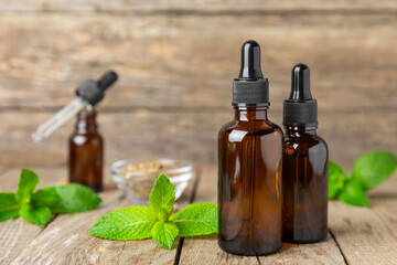 Essential oil mint on a wooden background. Peppermint essential oil with fresh mint leaves. A bottle of aromatherapy oil. Mint extract. The concept of natural cosmetics, spa care. copy space