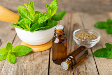Essential oil mint on a wooden background. Peppermint essential oil with fresh mint leaves. A...