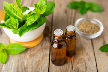 Essential oil mint on a wooden background. Peppermint essential oil with fresh mint leaves. A bottle of aromatherapy oil. Mint extract. The concept of natural cosmetics, spa care. copy space