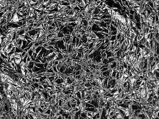 Crinkled metallic foil with a textured pattern of reflective surfaces and sharp creases, creating a visually complex and chaotic arrangement, ideal for abstract or industrial themes