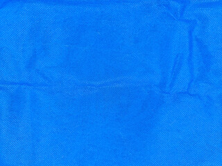 Bright blue textured fabric with subtle wrinkles and a grainy surface pattern, showcasing variations in shading and light. The material appears soft and is evenly distributed
