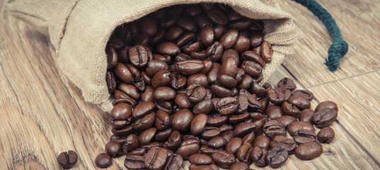 Heap of dark roasted coffee grains in jute bag