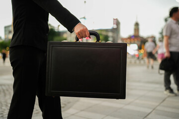 Business in Motion: An individual in a dark suit strides confidently through a bustling urban...