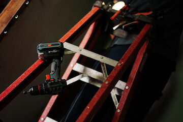 Construction worker using power drill on ladder indoor workspace high-efficiency task focused...