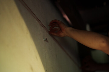 Hand engaging with wall texture indoor setting close-up shot dim lighting artistic exploration