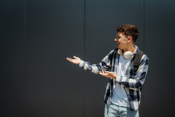 Portrait of a young adult man student smile showing something on his right copy space
