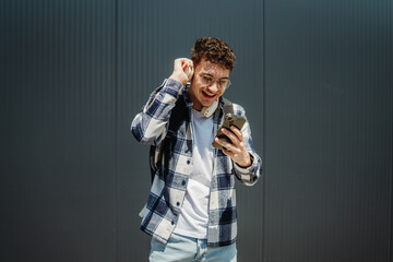 Portrait of a young adult man student smile using smartphone 
