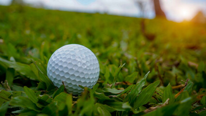 Golf ball is on a green lawn in a beautiful golf course with morning sunshine.