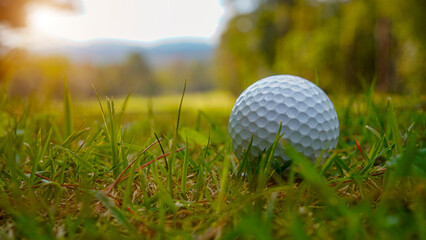 Golf ball is on a green lawn in a beautiful golf course with morning sunshine.