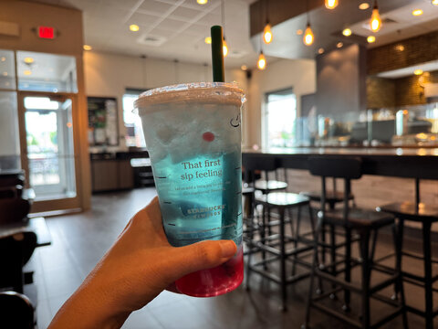 Crystal, Minnesota - May 30, 2025: Hand holds a summer berry refresher drink inside of a Starbucks coffee shop