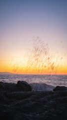 Waves crashing on rocks at sunset creating stunning water droplets