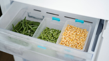 Frozen vegetables preserving freshness in refrigerator drawer: peas, green beans, and corn