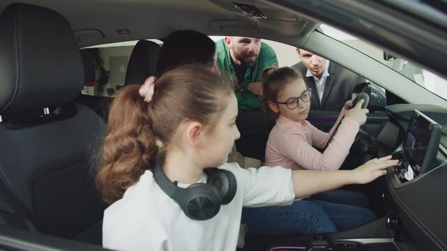 In a modern car dealership, a manager shows and advises a young family with children about buying or test driving a modern car. The concept of buying or leasing a new car.