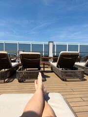 A person on a lounge chair on the a cruise ship overlooking the ocean.