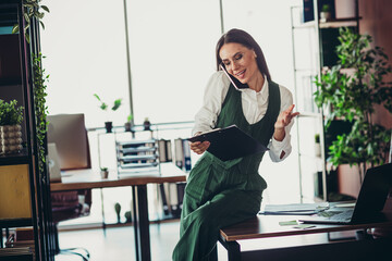 Confident businesswoman multitasking in the office showcasing productivity and elegance during her...