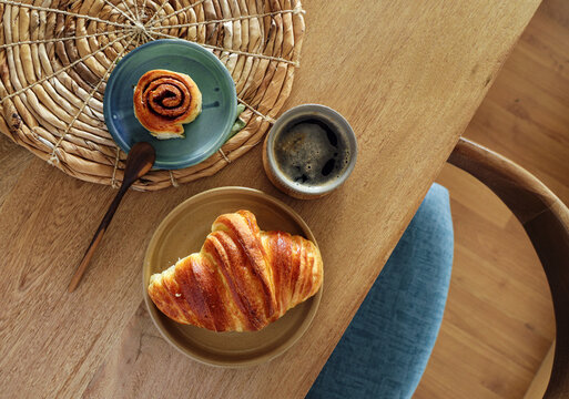 Breakfast view a bunch of croissant and a cup of coffee with cafe vibe background. Cafe menu, breakfast. Fresh pastries: croissants, rolls.