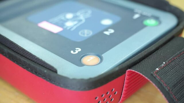 pressing the AED's shock button to deliver an electric shock to a heart attack patient