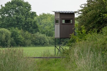 Wooden hunting blind overlooking green field and forest