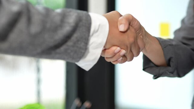 Hands of professional businessmen shaking hands successfully in business cooperation agreement, making a deal in modern office.