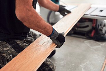 Professional handyman installing laminate flooring in a new apartment.