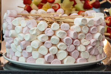 A variety of marshmallows arranged as a dessert on a buffet table. The soft, fluffy sweets in pastel colors create a playful and inviting presentation, perfect for festive events, celebrations