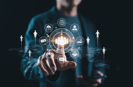 Target Audience and Digital Outreach Strategy Concept. Businessperson points at virtual interface with people icons and marketing symbols, representing audience targeting and global digital strategy.