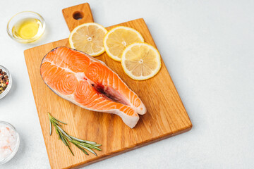 Fresh salmon steak prepared for grilling on a wooden cutting board