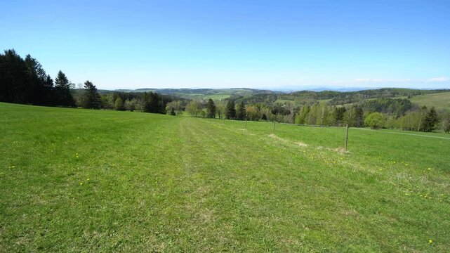 A walk across a meadow alongside an electric rope fence in a vast valley on a sunny day